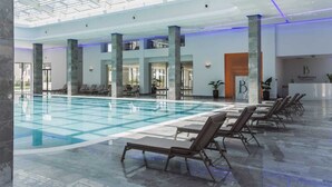 Una gran piscina interior amb gandules, sostre de vidre i una zona de recepció amb el rètol 'Bamboo'.