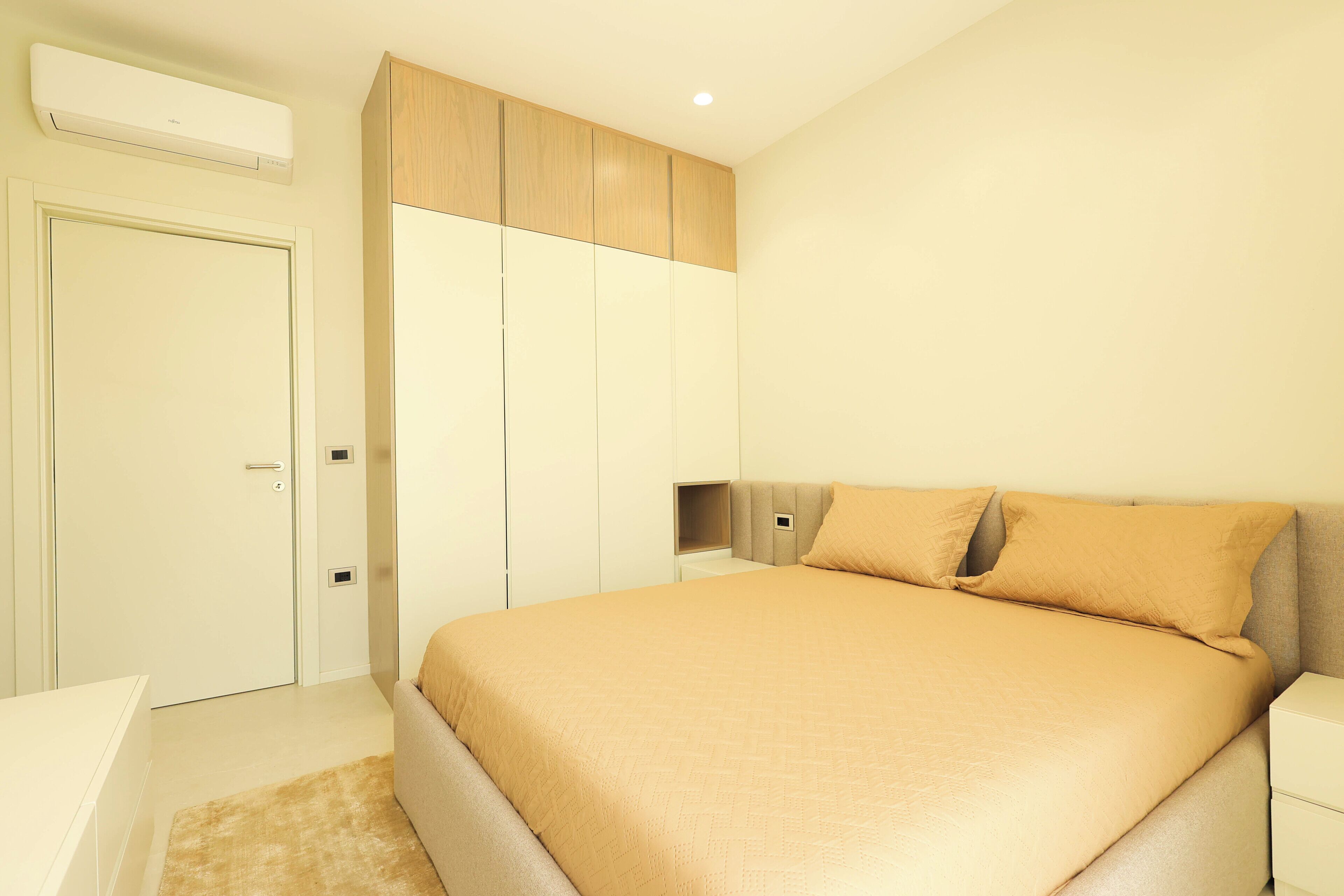 Un dormitorio con una cama, un armario y una mesita de noche.