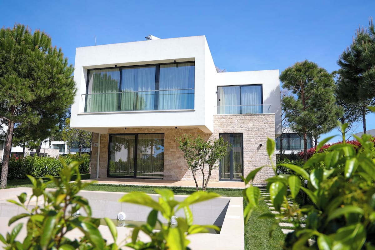 A modern two-story house with large windows, a stone facade, and a well-maintained garden.