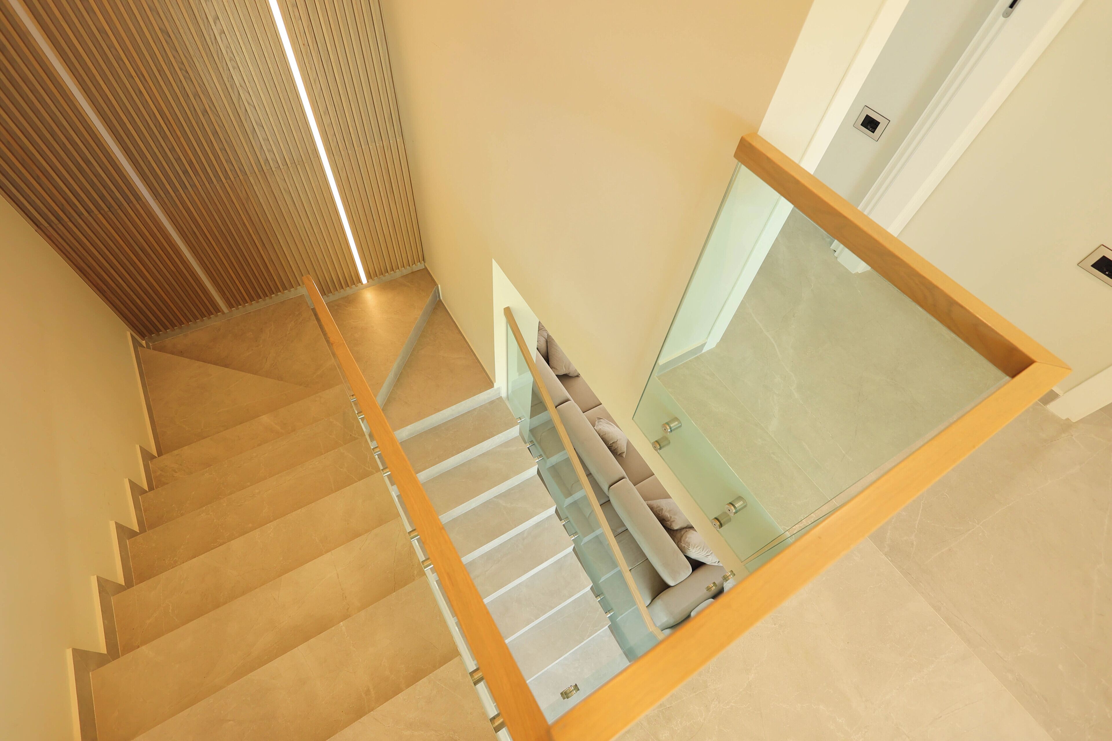 A modern staircase with glass railings and beige carpeted steps.