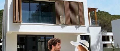 Una casa moderna de dos pisos con fachada de vidrio y zona de piscina.