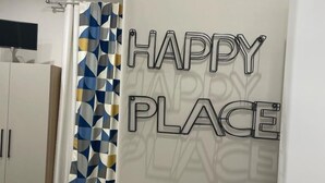 A room with a bed, a wardrobe, a TV, and a door with 'HAPPY PLACE' sign. - Miambra (Grumo Nevano)