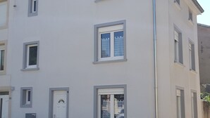 Un edificio de varios pisos con fachada plana, varias ventanas y una puerta visible.