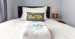 Restful retreat with a made bed, bedside table, and lamp.