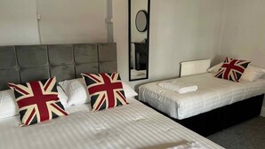 Une chambre d’hôtel avec deux lits, chacun étant équipé de draps et d’oreillers blancs ornés du motif Union Jack.
