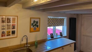 Une cuisine équipée d’un évier, d’une fenêtre donnant sur un beau paysage et d’un mur orné de tableaux encadrés.