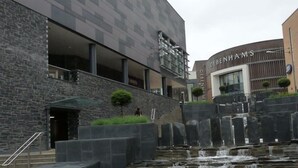 Un edificio moderno con fachada de piedra y una fuente ornamental al frente.