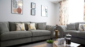 A modern living room with two grey sofas, a wooden coffee table, and a small side table. - The Flintshire - 3 Bedroomed House - Flint (Flint)