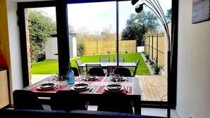 Een eetruimte met een tafel voor zes personen, grote ramen en uitzicht op een achtertuin.