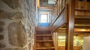 A wooden staircase in a stone-walled room leading to a kitchen area with wooden cabinets and a window. - Wish Suites Bodrum Hotel (Bodrum)