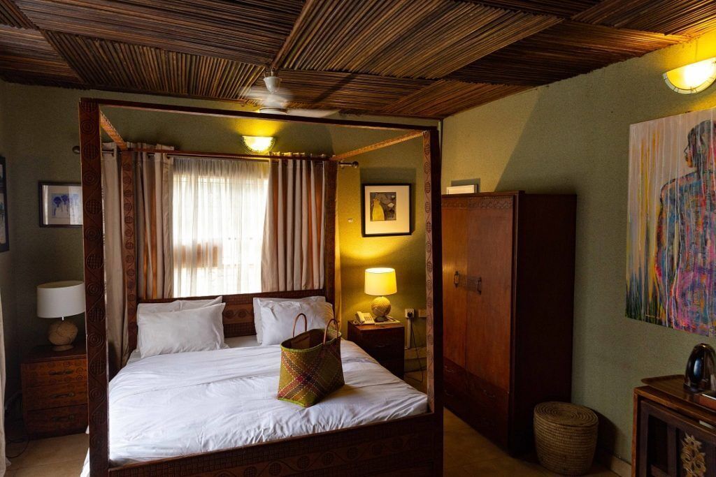 A four-poster bed with a canopy, a bedside lamp, a wooden nightstand, and a framed picture on the wall.