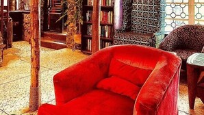 Un salon chaleureux avec un fauteuil rouge, une bibliothèque et un fauteuil à motifs.