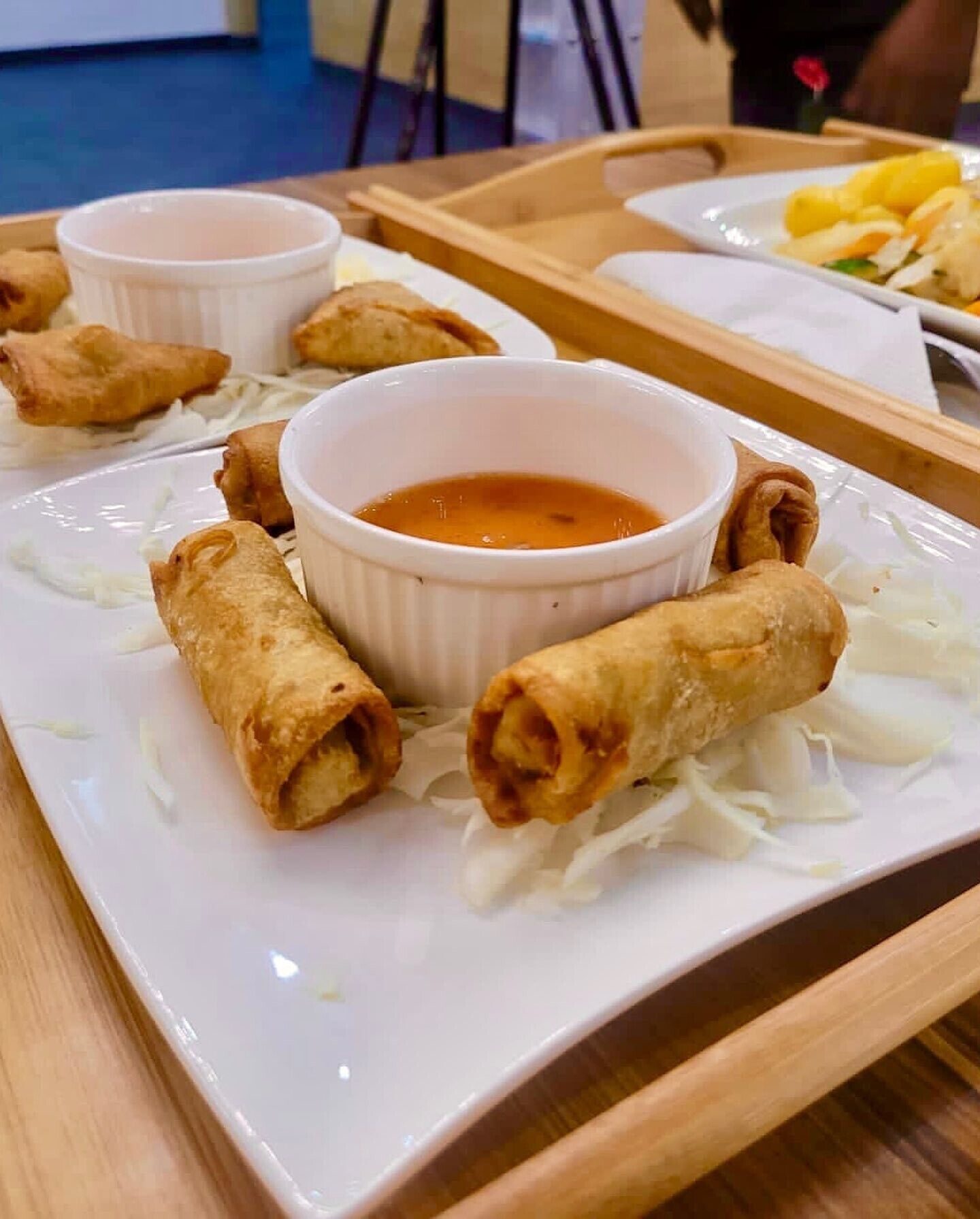 A tray with spring rolls and a dipping sauce on a white plate.