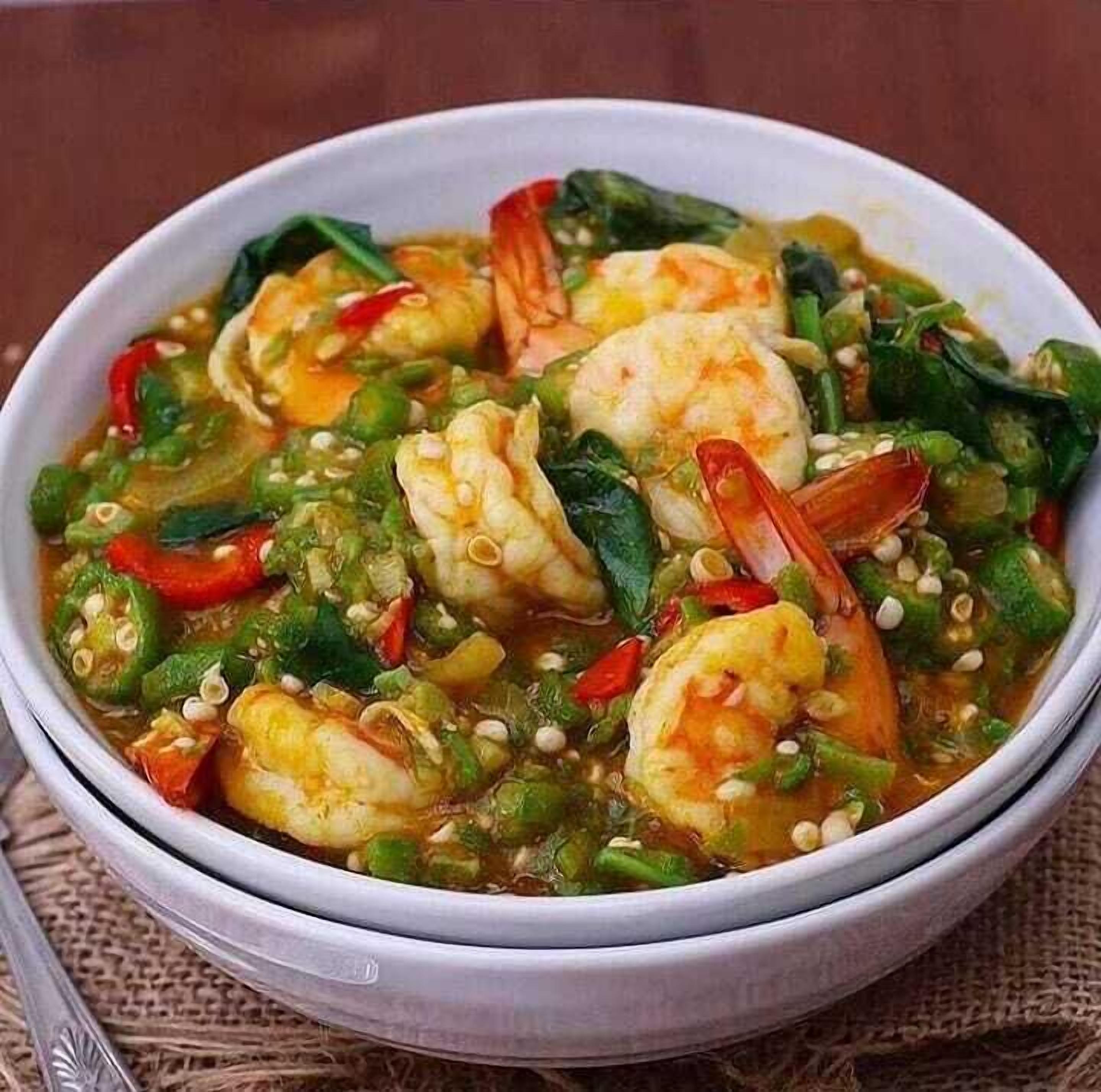 Un tazón de camarones y verduras en caldo.