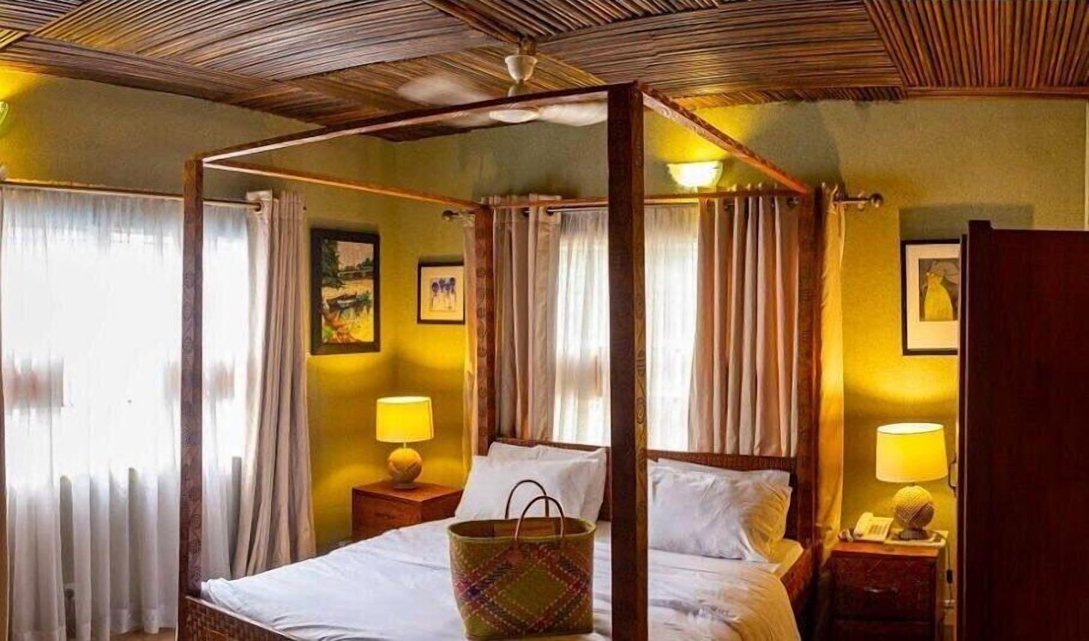 A four-poster bed with a canopy, two bedside lamps, and a bedside table with a lamp.