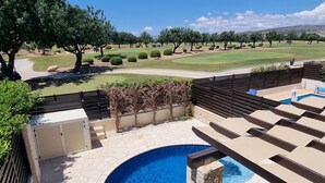 A backyard with a swimming pool, lounge chairs, and a view of a golf course. - Villa Nausicaa, Aphrodite Hills Golf Resort, Private Heated Pool With Jacuzzi (Kouklia)