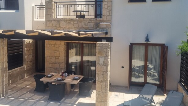 A two-story house with a swimming pool, outdoor seating, and a stone wall. - Villa Nausicaa, Aphrodite Hills Golf Resort, Private Heated Pool With Jacuzzi (Kouklia)