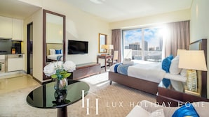 Ein Hotelzimmer mit Bett, Fernseher, Schreibtisch und Blick auf die Stadt.