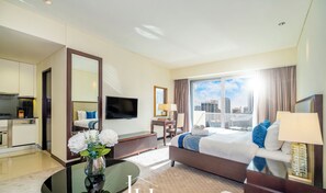 Habitación de hotel con cama, televisión, escritorio y vistas a la ciudad.