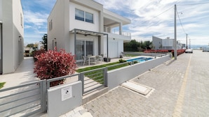 A modern two-story house with a covered patio, a swimming pool, and a paved driveway.