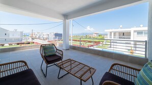 Un balcón con mobiliario de mimbre, vistas a edificios y cielo despejado.