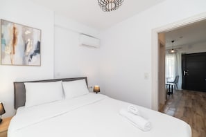Hotellihuone, jossa on sänky, taulu, ilmastointilaite ja näkymä ruokailutilaan.