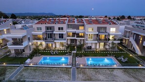 Un hôtel moderne à plusieurs étages, doté de terrasses sur le toit, d’une piscine et offrant une vue sur la mer.