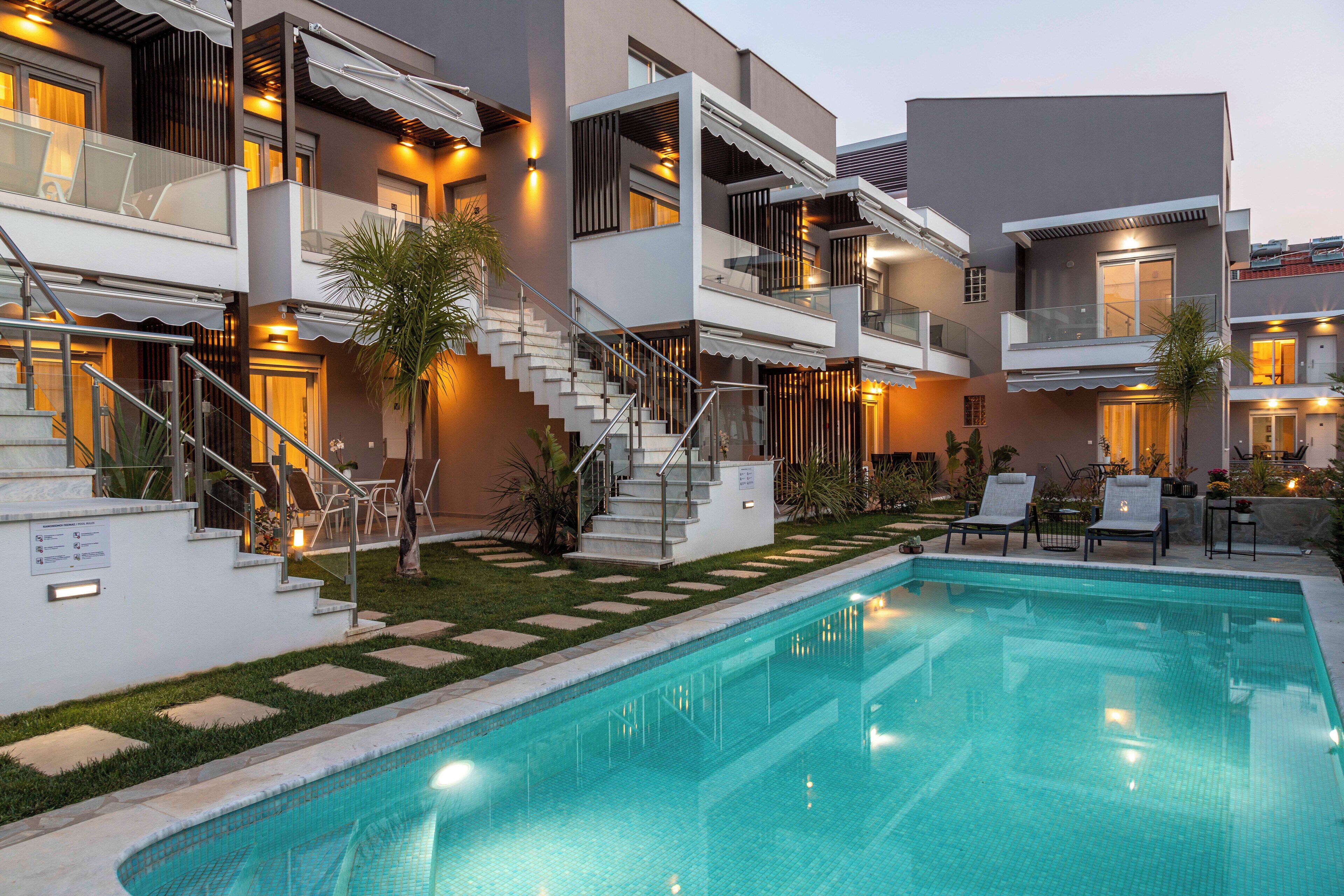A modern hotel with a swimming pool, multiple balconies, and outdoor seating areas.