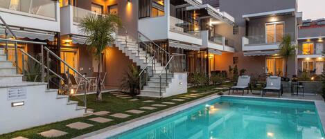 A modern hotel with a swimming pool, multiple balconies, and outdoor seating areas.