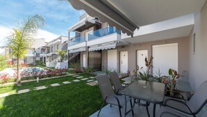 Un immeuble résidentiel moderne doté d’un patio couvert, d’une piscine et d’un jardin bien entretenu.