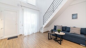 Una sala de estar moderna con una escalera, un sofá y una pequeña mesa con una planta.