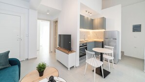 Un apartamento moderno con sala de estar, comedor, kitchenette y televisor.