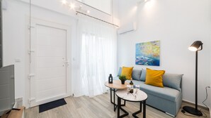 Una sala de estar moderna con un sofá, una mesa de centro, un televisor y una lámpara de pie.