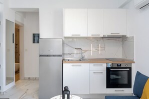 A modern kitchen with white cabinets, a built-in oven, and a marble backsplash.