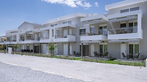 A modern multi-story hotel with balconies, outdoor seating, and a paved walkway. - Nefeli -Two Bedroom Apartment (Kavala)