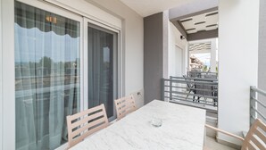 A balcony with a table and chairs, a sliding glass door, and a view of the outside. - Nefeli -Two Bedroom Apartment (Kavala)