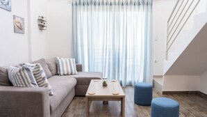 Un salon moderne avec un canapé gris, des coussins à rayures, une table basse en bois et un escalier.