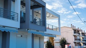 Un immeuble moderne à plusieurs étages, doté de balcons, d’un toit plat et surplombant un ciel dégagé.