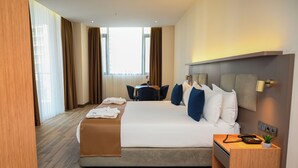A modern hotel room with a large bed, a desk, and a chair. - New wave apart hotel (Batumi)