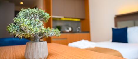 A small potted bonsai tree on a wooden table in a hotel room.