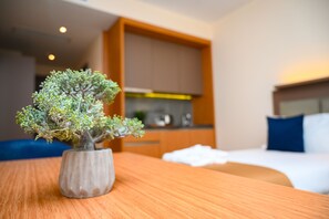 A small potted bonsai tree on a wooden table in a hotel room. - New wave apart hotel (Batumi)