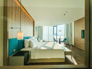 A modern hotel room with a large bed, a seating area with a table, and a view of the sea. - Ha Long Bay Luxury Homestay (Bai Chay)