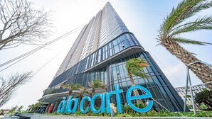 A modern building with a prominent 'Accarte' sign, featuring a glass facade and surrounded by palm trees. - Ha Long Bay Luxury Homestay (Bai Chay)