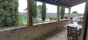 Un espacio al aire libre techado con paredes de piedra, una mesa y sillas.