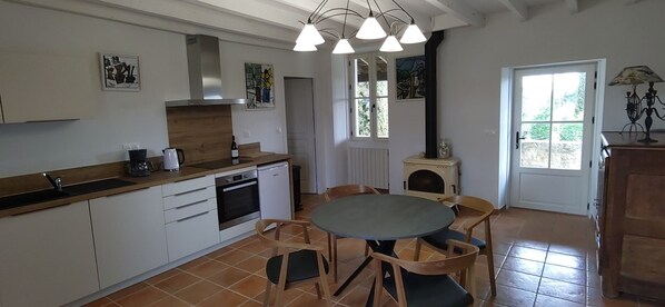 A kitchen with white cabinets, a built-in oven, a coffee maker, and a dining table with chairs.
