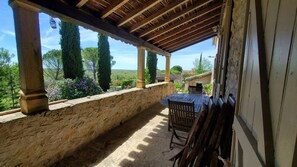 A covered patio with stone walls, wooden pillars, and a table with chairs.