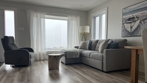Ein modernes Wohnzimmer mit einem grauen Sofa, einem Holztisch und einem grauen Sessel.