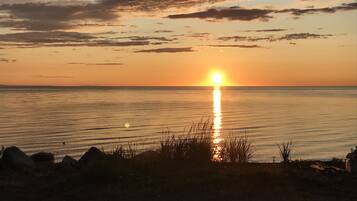A sunset over a calm body of water with a rocky shoreline in the foreground.