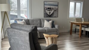 Ein modernes Wohnzimmer mit einem grauen Sofa, einem Holztisch und einem Esstisch mit Stühlen.