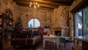 Habitació de parets de pedra amb una llar de foc, una taula de fusta, un sofà i un arbre de Nadal.